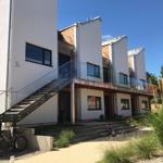 Moderne Wohnung mit Glasbrüstung und Holzverkleidung. Außentreppe und begrünte Fläche.