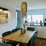 Essbereich mit Holztisch, Stühlen und Küchenzeile im Hintergrund.