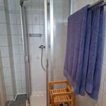 Dusche mit Duschbank, Handtuchhalter und Holzregal