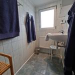 Badezimmer mit Waschbecken, Fenster, Handtuchhaltern und Bodenfliesen.