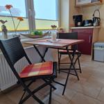 Essbereich mit Tisch, zwei Stühlen und Küchenzeile mit Mikrowelle und Kaffeemaschine.