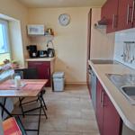 Küche mit roten Schränken, Esstisch und Küchenzeile