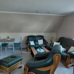 Wohnzimmer mit dunkelgrünem Ledersofa, Esstisch und Fenster