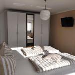 Schlafzimmer mit Bett, Kleiderschrank und Wand-TV.