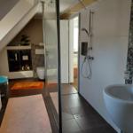 Badezimmer mit Dusche, Waschbecken und Toilette unter Dachschrägen.