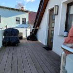 Terrasse mit Holzdeckung, Geländer und geschlossenen Möbeln.
