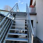 Metalltreppe führt zu einer Terrasse an der Hauswand.
