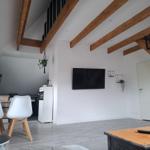 Wohnzimmer mit Holzbalken, Fernseher und Essbereich.