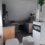 Küche mit Arbeitsplatten, Spüle, Kochfeld und Kühlschrank.