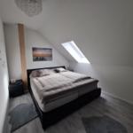Schlafzimmer mit Dachschrägen, Bett, Fenster und Wandbild.