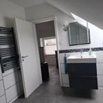 Badezimmer mit Waschbecken, Spiegel und Heizkörper an der Wand.