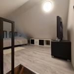 Schlafzimmer mit Dachschrägen, Bett, TV und Holzboden.