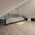 Schlafzimmer mit Dachschrägen, Bett, Kleiderschrank und Teppich.