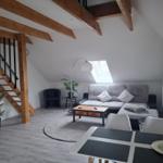 Wohnraum mit Dachschrägen, Sofa, Tisch und Stühlen. Treppenaufgang zur oberen Etage.