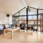 Living room with wooden ceiling, large window, and sofa with cushions.