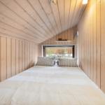 Bedroom with wooden walls and bed under sloped ceiling