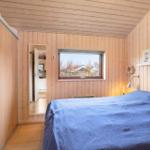 Bedroom with wooden walls, bed, and window for outdoor view.
