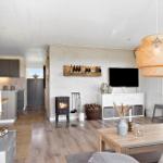 Living area with fireplace, TV, and dining table. Kitchen in the background.