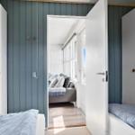 Two bedrooms with view into living area with sofa and windows.