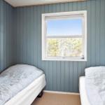 Two beds in a room with blue walls and a window.
