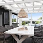 Terrace with white table, dark chairs, and hanging wicker lamps.
