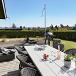 Terrace with table, chairs, grill, and view of green lawn.