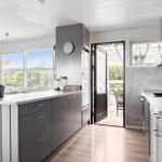 Kitchen with gray cabinets, wooden floor, and view of balcony.