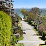 Drive to vacation rental with sea view and green trees.