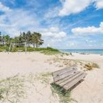 Wooden bench on sandy beach with view of sea and playground.