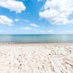 White sandy beach with turquoise sea and blue sky with white clouds.