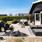 Deck with grill, table, chairs, and loungers in front of a house.