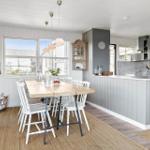 Kitchen with dining area, wooden table, white chairs, and gray cabinets.