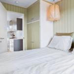 Bedroom with bed, coat rack, and view into the kitchen.