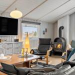 Wohnzimmer mit Kamin, Sofa, Sessel und Fernseher an Wand.