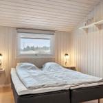 Schlafzimmer mit Bett, Fenster und Holzwandverkleidung.