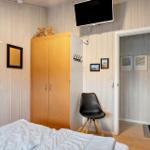 Schlafzimmer mit Bett, Kleiderschrank, TV und Stuhl.