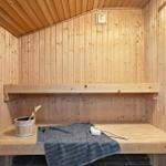 Sauna mit Holzwand, Sitzbank und Holzwaschbecken.