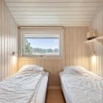 Zwei Betten in einem Holzraum mit Fensterblick auf Wald.