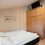 Schlafzimmer mit Bett, Kleiderschrank und Fernseher an der Wand.