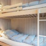 Doppelstockbett mit Matratzen und hellblauen Kissen in Holzwandnische.