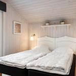 Schlafzimmer mit Doppelbett, Holzwand und Fensterblick auf Außengelände.