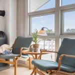 Zwei Sessel und ein Kamin stehen vor großen Fenstern mit Blick auf den Außenbereich.