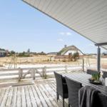 Terrasse mit Tisch und Stühlen, Blick auf eine Landschaft mit einem Dachstuhlhaus.