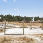 Haus mit Fußballtor und weißem Zaun auf sandigem Grund.