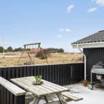 Terrasse mit Tisch, Grill und Schaukel im Freien.