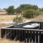 Terrasse mit Tisch und Stühlen, umgeben von Hecken und Gras.