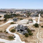Haus mit Terrasse und Grillplatz in dünner Vegetation.