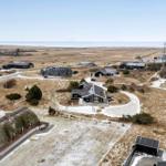Übersicht über mehrere Häuser auf einer trockenen, schneebedeckten Landschaft mit Blick auf das Meer.