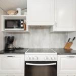 Küche mit weißen Schränken, schwarzer Arbeitsplatte und integriertem Herd.