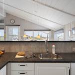 Küche mit Arbeitsplatte, Spüle und Fenstern zum Blick ins Freie.